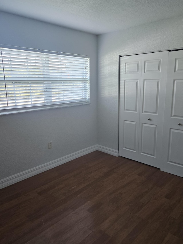 unfurnished bedroom featuring dark hardwood / wood-style flooring and a closet