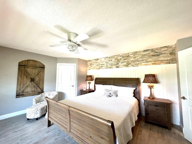 bedroom with hardwood / wood-style flooring, a textured ceiling, and ceiling fan