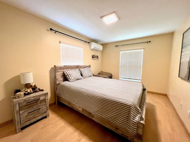 bedroom with a wall unit AC and light hardwood / wood-style flooring