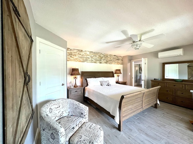 bedroom with a wall mounted air conditioner, a textured ceiling, ceiling fan, and a closet