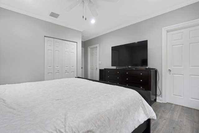 bedroom with crown molding, ceiling fan, wood-type flooring, and a closet