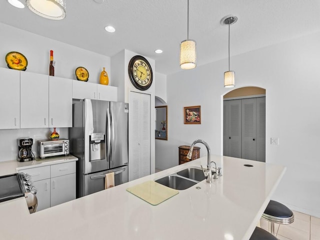 kitchen featuring a toaster, hanging light fixtures, stainless steel refrigerator with ice dispenser, a sink, and range with electric stovetop