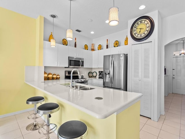 kitchen featuring appliances with stainless steel finishes, arched walkways, a peninsula, and light tile patterned floors