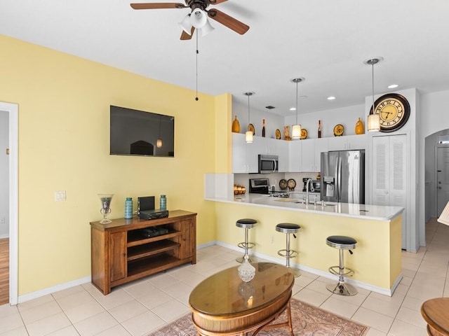 kitchen featuring appliances with stainless steel finishes, a breakfast bar area, a peninsula, light countertops, and light tile patterned flooring