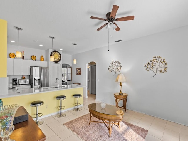 kitchen with arched walkways, decorative light fixtures, stainless steel refrigerator with ice dispenser, a breakfast bar area, and light tile patterned floors