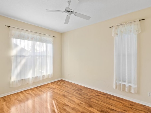 unfurnished room with wood finished floors, a ceiling fan, and baseboards