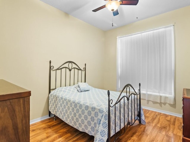 bedroom with a ceiling fan, baseboards, and wood finished floors