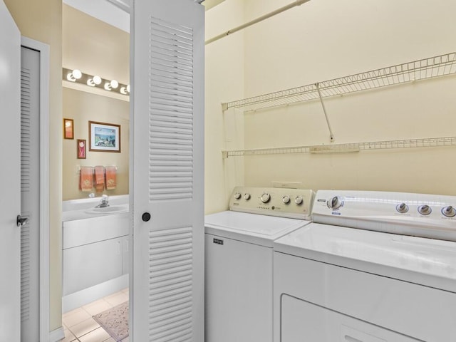clothes washing area with light tile patterned floors, laundry area, independent washer and dryer, and a sink