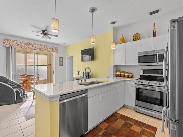 kitchen featuring light tile patterned floors, stainless steel appliances, a peninsula, a sink, and visible vents