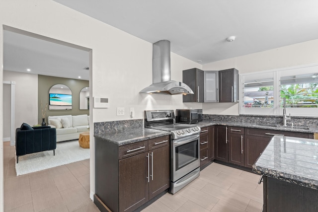 kitchen with sink, dark brown cabinets, dark stone countertops, island exhaust hood, and stainless steel electric stove