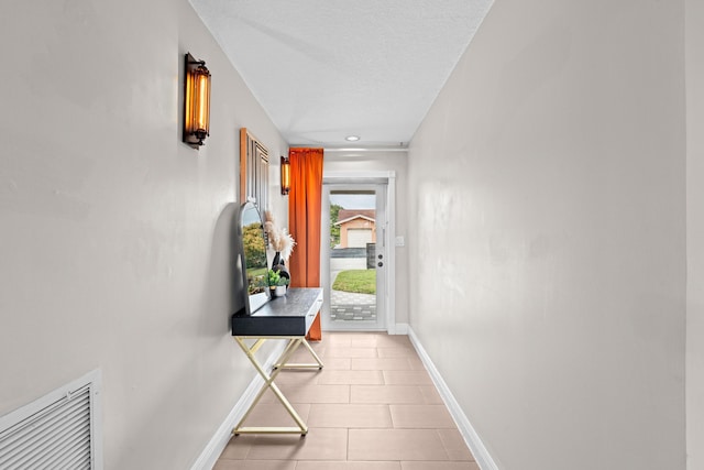 corridor featuring light tile patterned floors and a textured ceiling