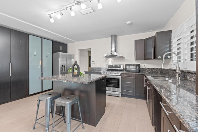 kitchen featuring sink, a breakfast bar area, a kitchen island, stainless steel appliances, and wall chimney range hood