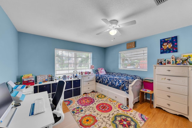 bedroom with light wood-type flooring, a textured ceiling, and ceiling fan