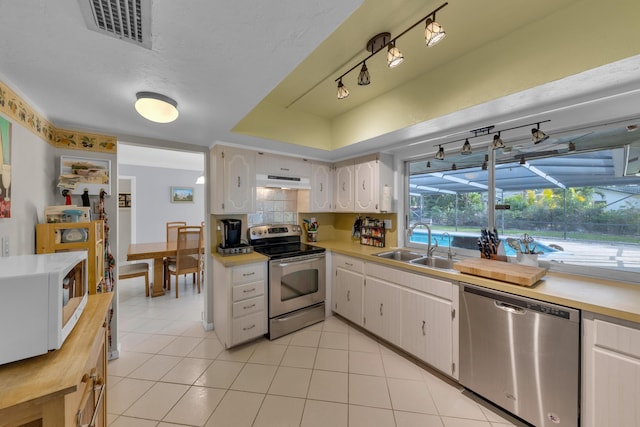 kitchen featuring white cabinetry, stainless steel appliances, light tile patterned flooring, and sink