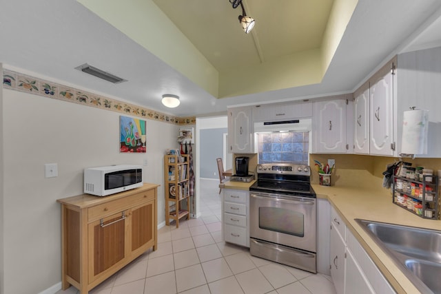 kitchen with stainless steel electric stove, light tile patterned flooring, white cabinetry, sink, and a raised ceiling