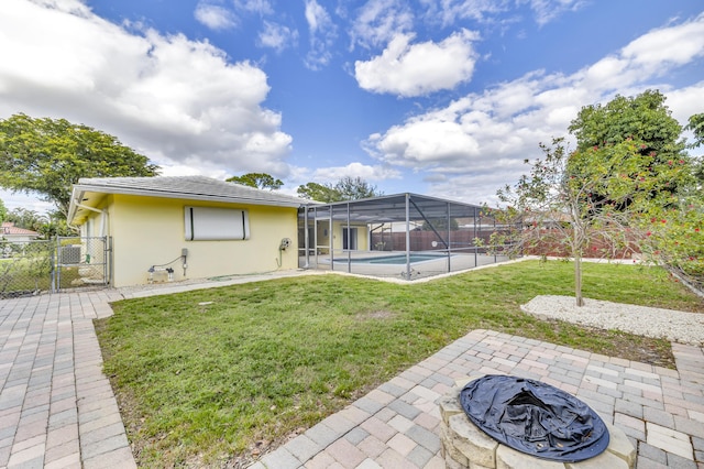 rear view of property with a lawn, a fire pit, a lanai, a fenced in pool, and a patio area