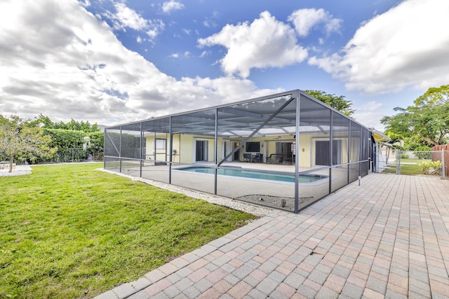 view of swimming pool featuring a yard, a patio area, and glass enclosure