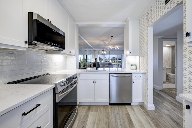 kitchen with stainless steel appliances, white cabinetry, sink, and light hardwood / wood-style flooring