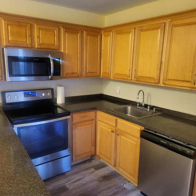 kitchen with appliances with stainless steel finishes, dark hardwood / wood-style flooring, sink, and decorative backsplash