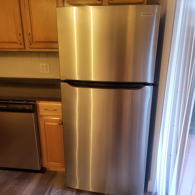 kitchen with tasteful backsplash, appliances with stainless steel finishes, and dark wood-type flooring