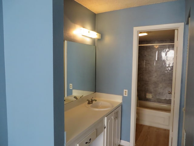 bathroom with vanity, tiled shower / bath combo, wood-type flooring, and a textured ceiling