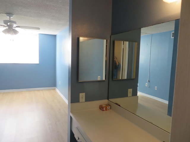 bathroom with ceiling fan, hardwood / wood-style flooring, and a textured ceiling