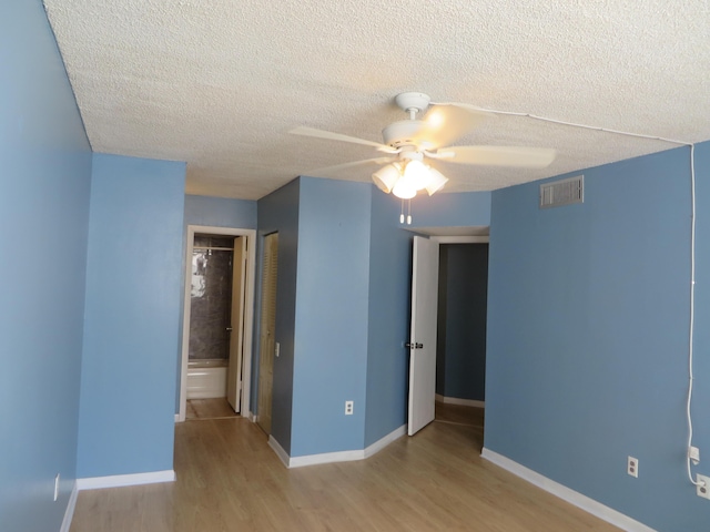 empty room with a textured ceiling, light hardwood / wood-style flooring, and ceiling fan