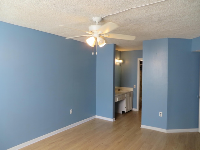 empty room featuring ceiling fan, sink, light hardwood / wood-style floors, and a textured ceiling