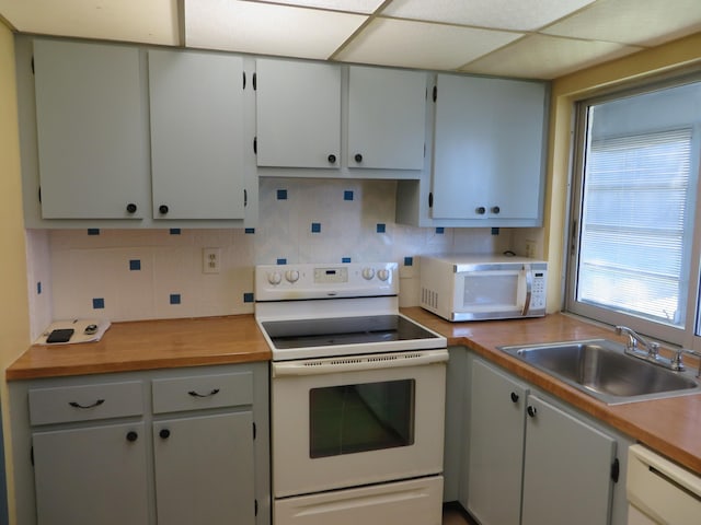 kitchen featuring sink, a drop ceiling, white cabinets, white appliances, and backsplash