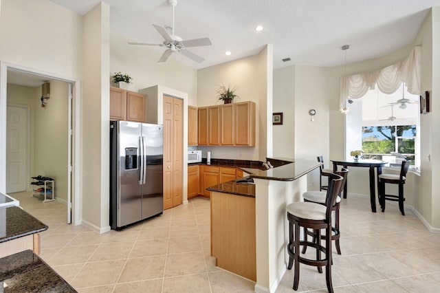 kitchen featuring stainless steel refrigerator with ice dispenser, decorative light fixtures, light tile patterned floors, kitchen peninsula, and ceiling fan