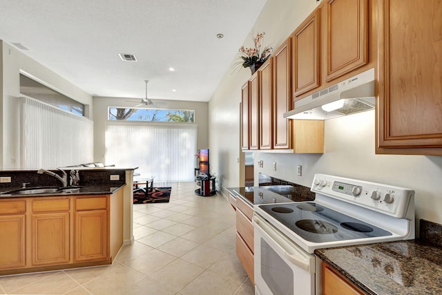 kitchen featuring ceiling fan, white electric range, sink, and dark stone countertops