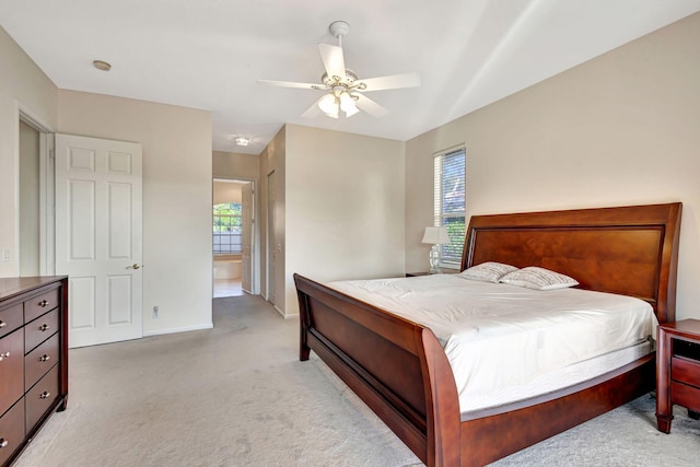 bedroom with ceiling fan, ensuite bathroom, and light carpet