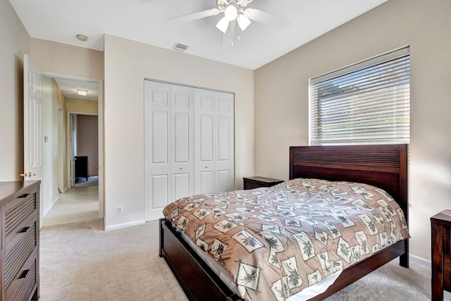 bedroom with ceiling fan, light colored carpet, and a closet