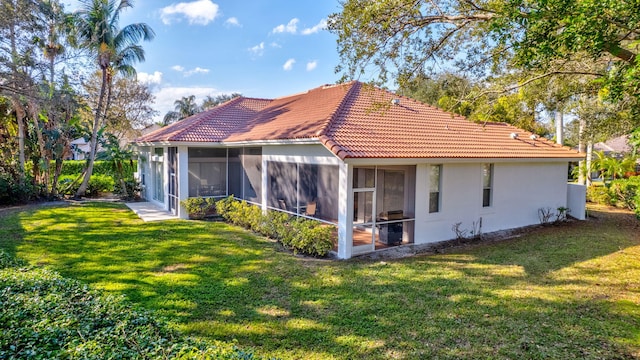 rear view of property featuring a sunroom and a lawn