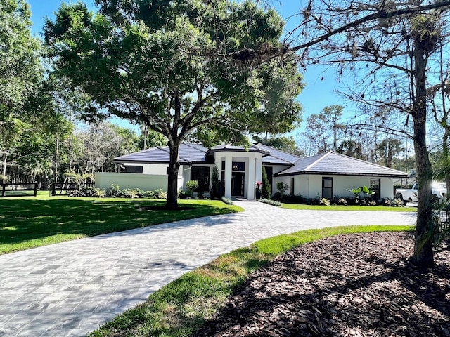 view of front of home featuring decorative driveway, a front lawn, and stucco siding