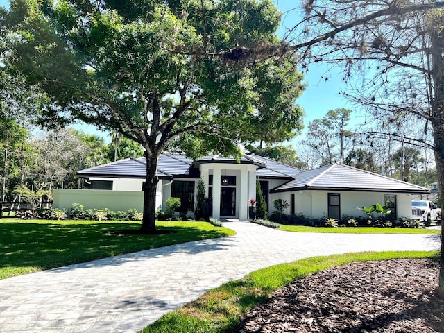 view of front facade featuring driveway, a front yard, a tile roof, and stucco siding