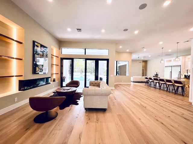 living area featuring built in features, recessed lighting, visible vents, light wood-style flooring, and baseboards