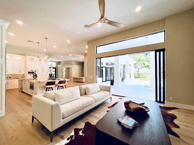 living room featuring a ceiling fan, recessed lighting, light wood-style flooring, and baseboards