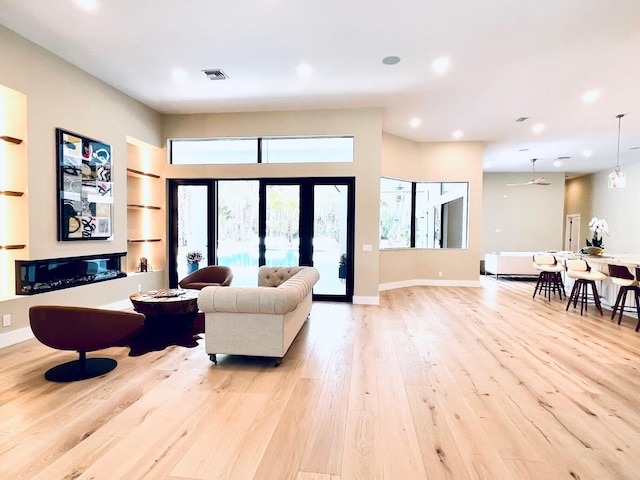 living area with light wood finished floors, recessed lighting, visible vents, and baseboards