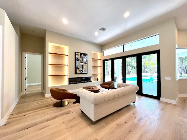 living room with visible vents, baseboards, built in features, light wood-type flooring, and recessed lighting