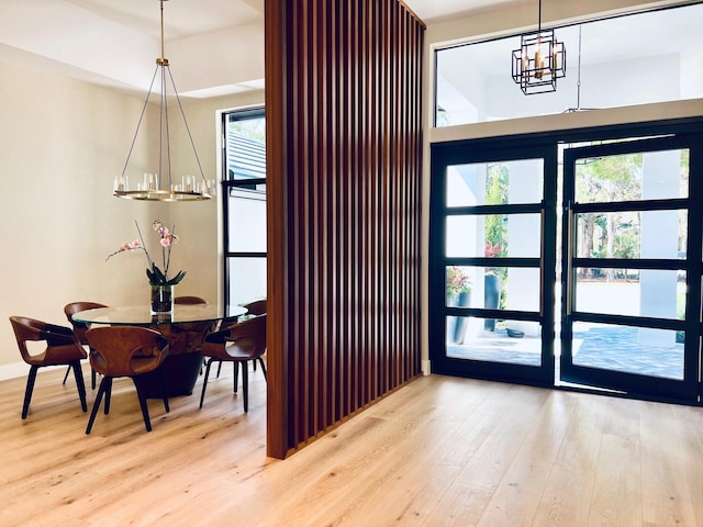 interior space with a healthy amount of sunlight, an inviting chandelier, and wood finished floors