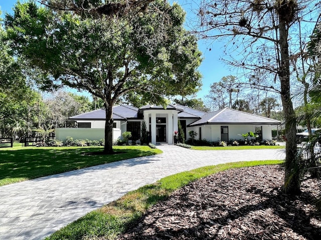 view of front of home featuring decorative driveway, a front yard, fence, and stucco siding