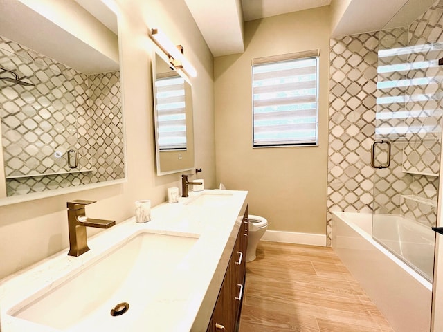 bathroom featuring double vanity, a sink, toilet, and wood finished floors