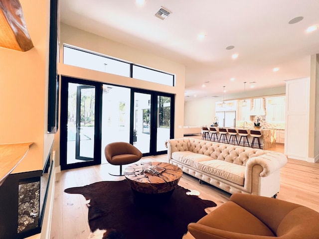 living room featuring light wood-style floors, baseboards, visible vents, and recessed lighting