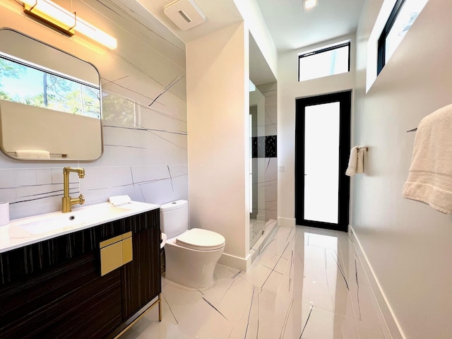 bathroom with baseboards, toilet, marble finish floor, a tile shower, and vanity