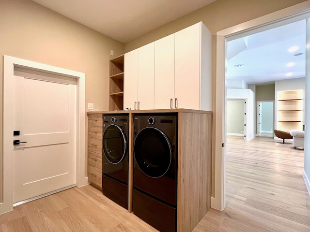 laundry area with cabinet space, washer and clothes dryer, and light wood finished floors