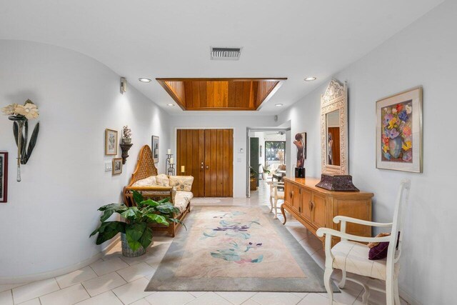 corridor featuring a tray ceiling and light tile patterned floors