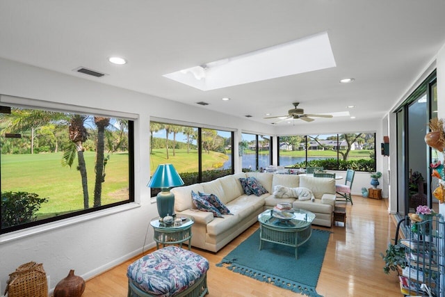 sunroom with a water view, ceiling fan, plenty of natural light, and a skylight