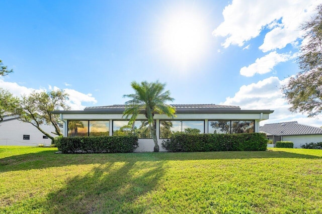 rear view of property with a yard and a sunroom