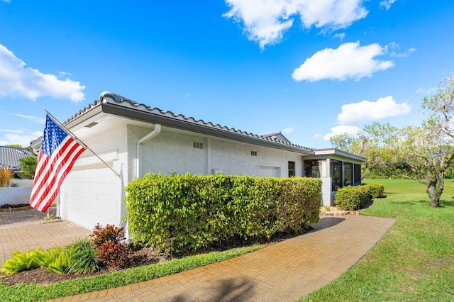 view of side of property featuring a yard, a sunroom, and a garage